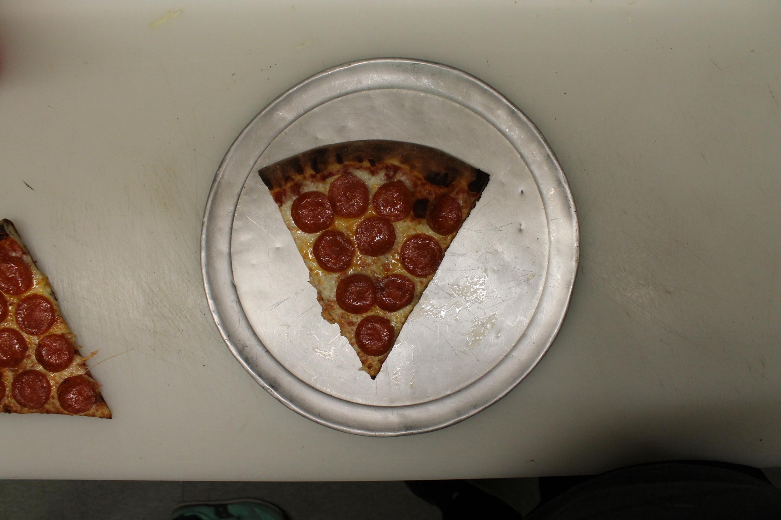 A slice of pepperoni pizza on a round metal tray