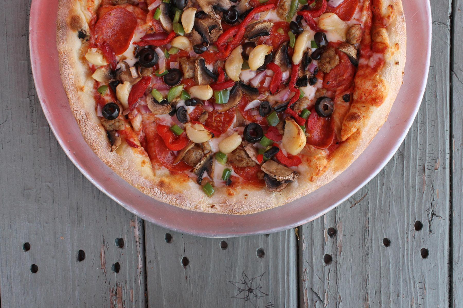 A freshly baked PieHole pizza covered with vegetables and pepperoni