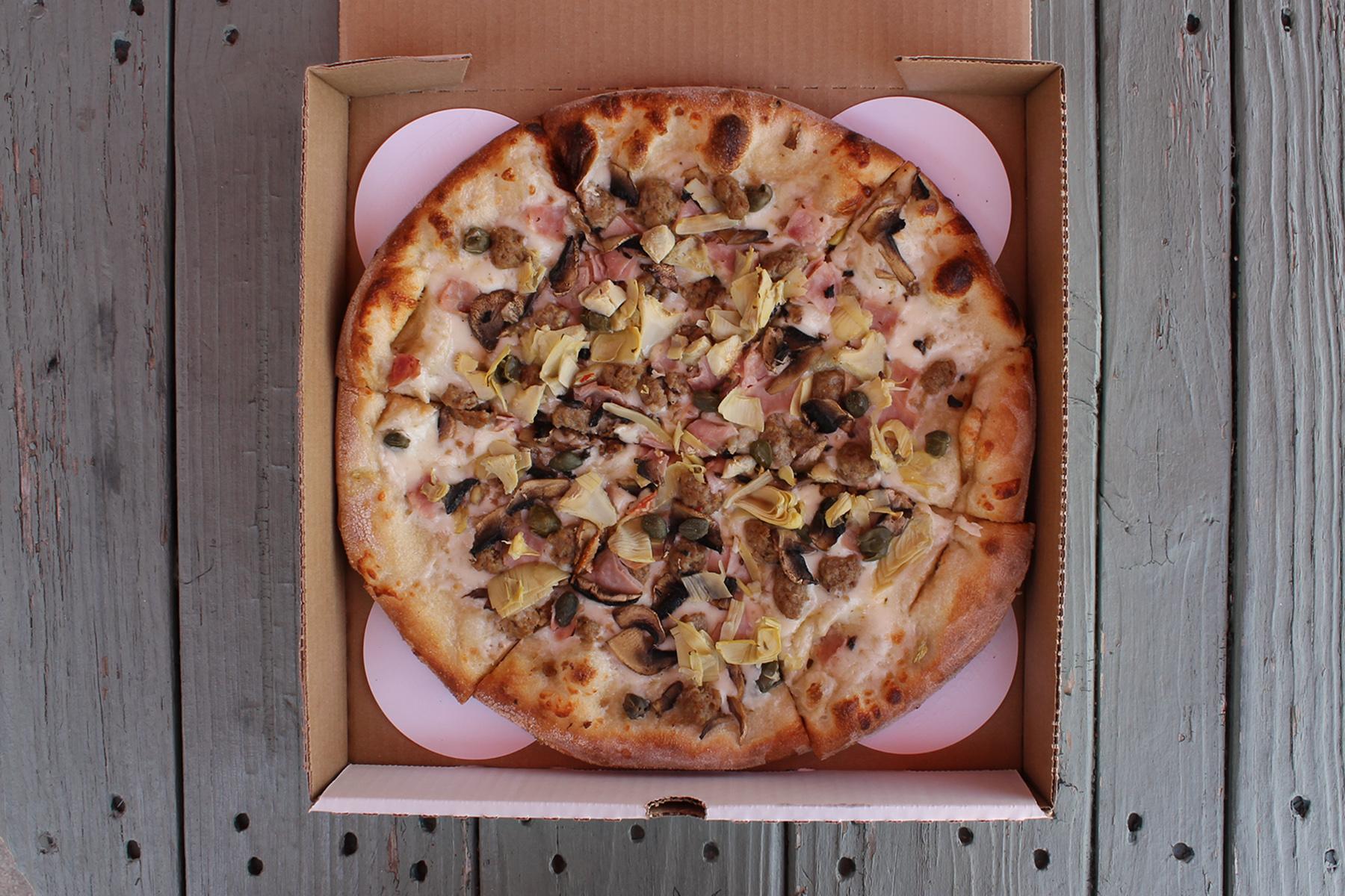 A white-sauce pizza in a takeout box